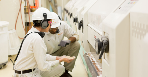 Two people checking a piece of milling equipment